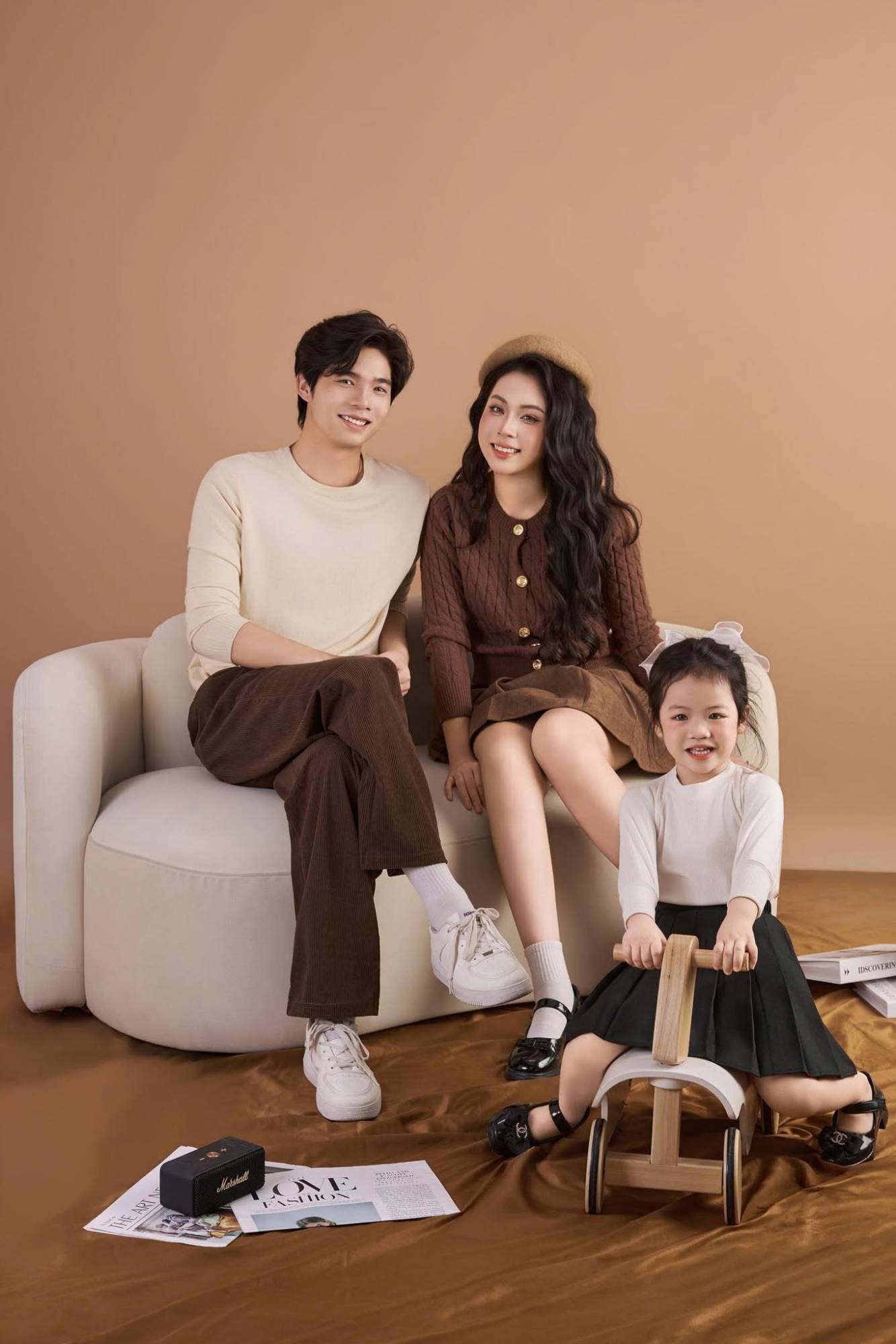 Bé gái ngồi xe gỗ trước bố mẹ trên sofa