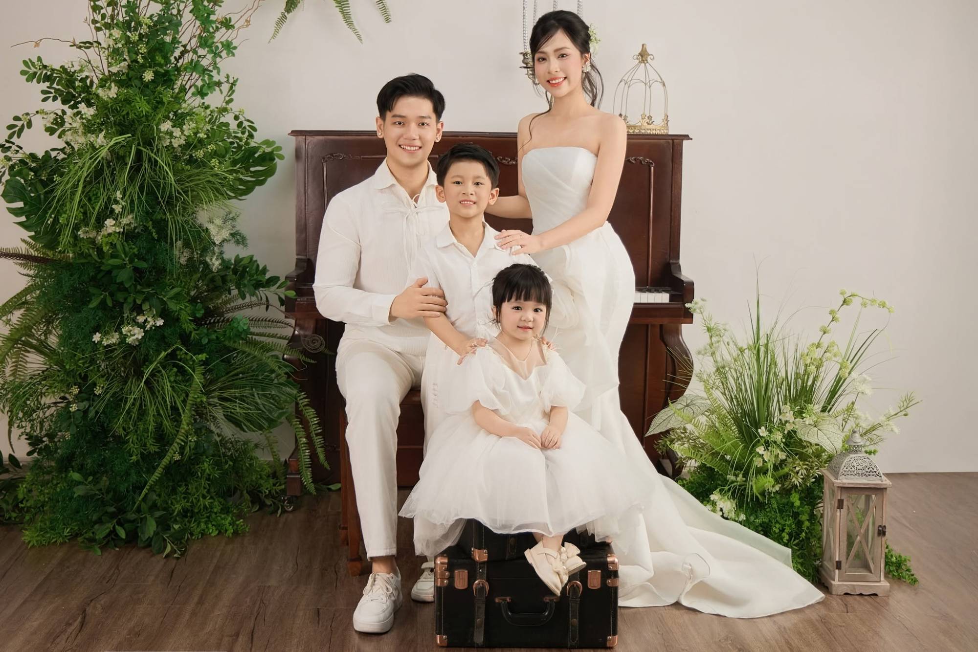 Gia đình bốn người áo trắng bên đàn piano